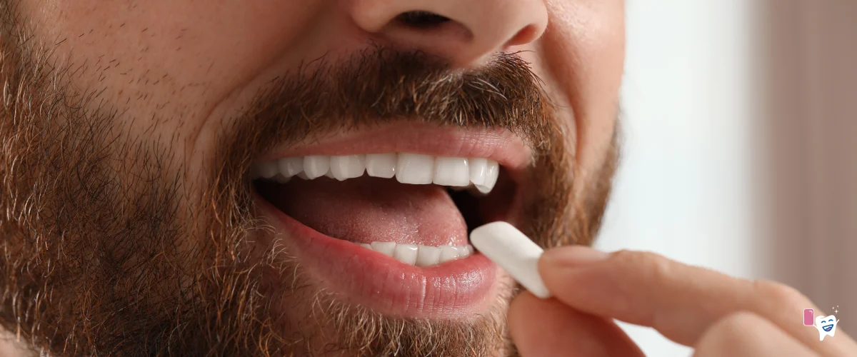 Picture of a man's head and his open mouth with healthy teeth putting a piece of gum in his mouth with his left hand | For the article: Healthy teeth with chewing gum | For the website: healthychewinggum.com | Source: shutterstock.com