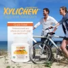 obrázek muže a ženy s koly procházejících se po pláži a popisem s výhodami žvýkaček a fotografie xylitolové ovocné žvýkačky v balení 60 žvýkaček od výrobce Xylichew bez aspartamu | Pro webové stránky: healthychewinggum.com | Zdroj: Xylichew