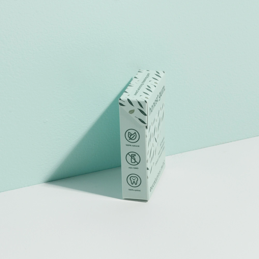 picture of Eucalyptus Mint All Nature Chewing Gum from honest gum in a flip box from the left front with 12 pcs on a green white background with a box shadow | Plastic free, sugar free, sustainable and aspartam free | For website: healthychewinggum.com | Source: honest gum