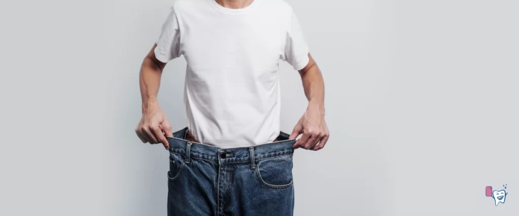 The picture shows a middle aged man with an oversized jeans around his waist, showing the loss of weight | For article: Weight Loss With Chewing Gum | For website: healthychewinggum.com | Source: shutterstock