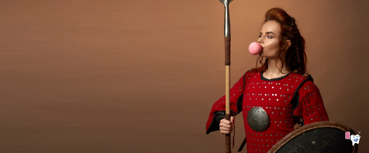 A girl warrior holding a lance and an armor blowing a chewing gum against a dark brown background | For article: Tracing the History of Chewing Gum | For website: healthychewinggum.com | Source: shutterstock