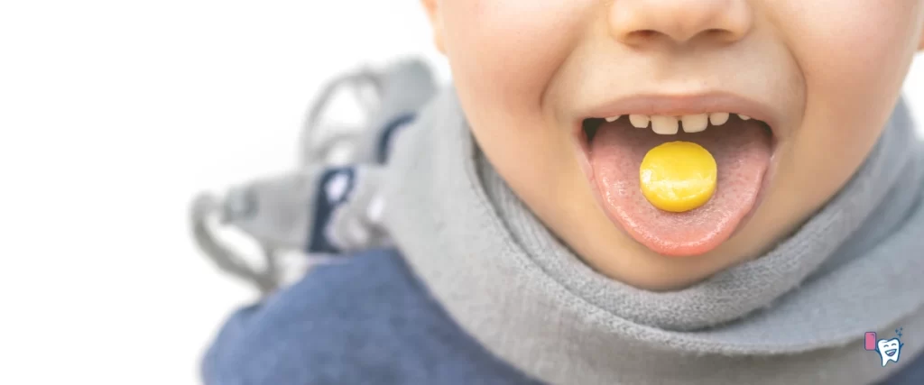 A young boy, wearing blue swearter and a muffler around his neck, has an orange lozenge on his tongue, standing against a white background| For article: You Should Start Using Healthy Lozenges: Find out why | For website: healthychewinggum.com | Source: shutterstock