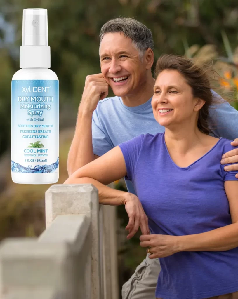 Senior cheerful man and woman couple smiling and looking out from bridge full of energy enjoying something - man holding woman around shoulder and hand supporting head, woman leaning her elbow on railing in background nature | Banner for Moisturizing Oral Spray to Fight Dry Mouth | For website: healthychewinggum.coim | Source: shutterstock.com