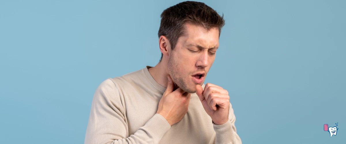 A young man frustrated with dry cough is holding his throat against a light blue background | | For article: Instant Relief for Dry Mouth and Dry Cough | For website: healthychewinggum.com | Source: shutterstock