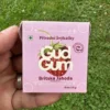 Jahodové přírodní žvýkačky Gud Gum bez plastových materiálů a bez škodlivé chemie (Britská jahoda) držené v ruce levou rukou na pozadí trávník zahrady