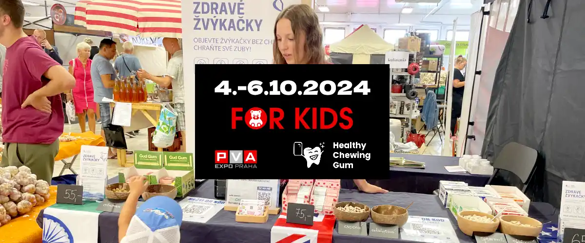 Fotografie v pozadí z výstavy - v popředí černý obdelník s informací o výstavě FOR KIDS 2024 na výstavišti PVA EXPO Praha - pozvánka pro všechny, kdo mají zájem o zdravé žvýkačky bez škodlivé chemie, bez aspartamu, bez cukru, bez syntetických konzervantů, barviv a sladidel