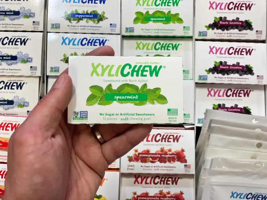 Xylichew spearmint chewing gum in a blister holding in the left hand in the background with other blisters with other flavours