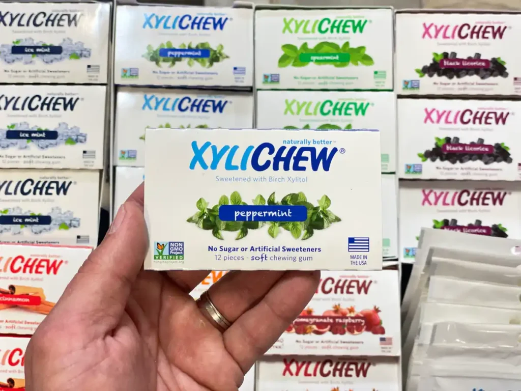 Xylichew peppermint chewing gum in a blister holding in the left hand in the background with other blisters with other flavours