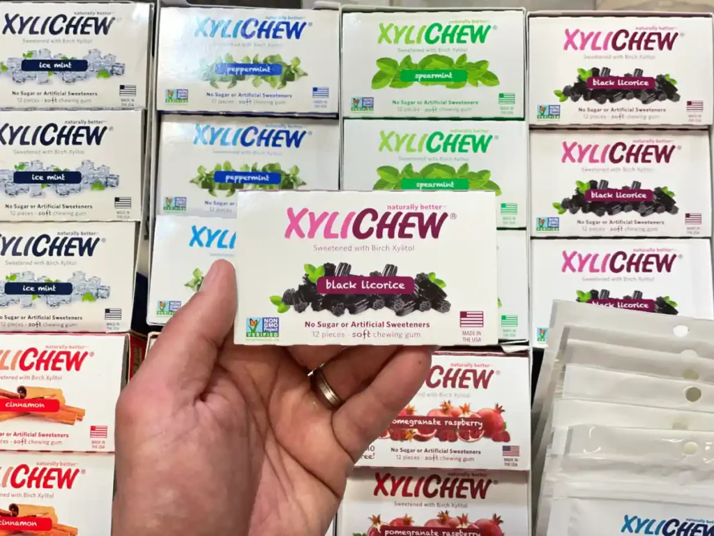 Xylichew licorice chewing gum in a blister holding in the left hand in the background with other blisters with other flavours