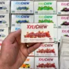 Xylichew pomegranate raspberry chewing gum in a blister holding in the left hand in the background with other blisters with other flavours