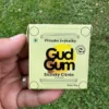 Citrónové přírodní žvýkačky Gud Gum bez plastových materiálů a bez škodlivé chemie držené v ruce levou rukou na pozadí trávník zahrady